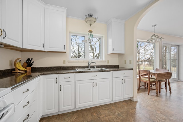 kitchen featuring crown molding, hanging light fixtures, a sink, stove, and white cabinetry