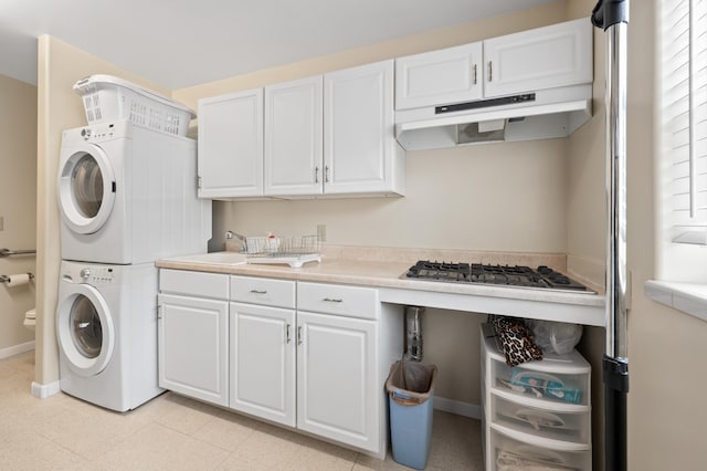 washroom with a sink, baseboards, and stacked washer and clothes dryer