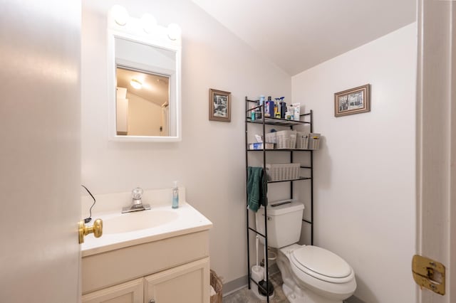 bathroom with toilet, baseboards, lofted ceiling, and vanity