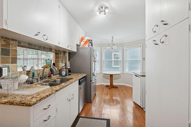 2613 Inglewood Ave S, Saint Louis Park, MN 55416 - kitchen with stainless steel dishwasher, light wood-style floors, white cabinets, and plenty of natural light