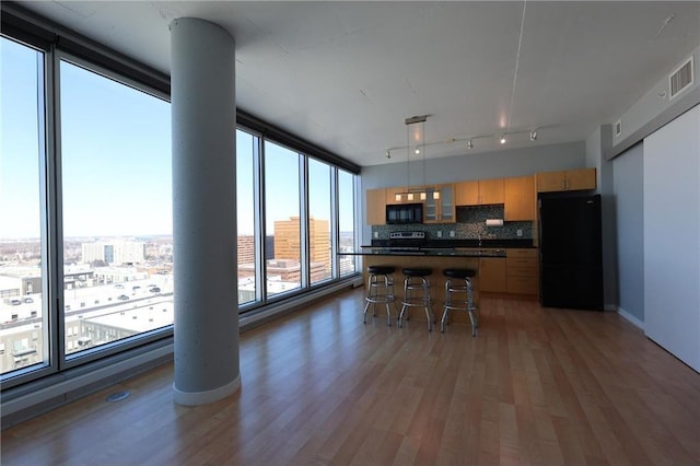 kitchen with dark countertops, visible vents, light wood finished floors, and black appliances