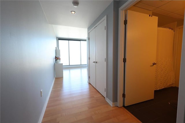 hall with baseboards and light wood-style flooring