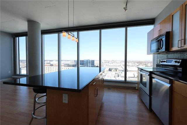 kitchen with a kitchen island, appliances with stainless steel finishes, dark wood finished floors, a city view, and a breakfast bar