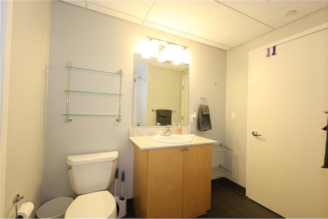 bathroom featuring tile patterned floors, a drop ceiling, vanity, and toilet