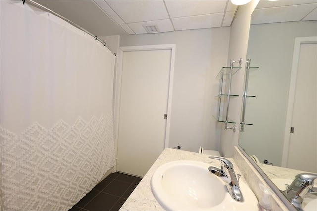 full bathroom with vanity, a drop ceiling, and tile patterned floors