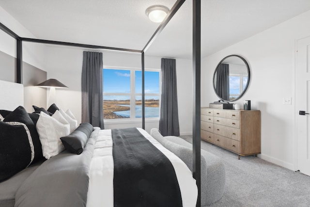 bedroom featuring baseboards, a water view, and light colored carpet