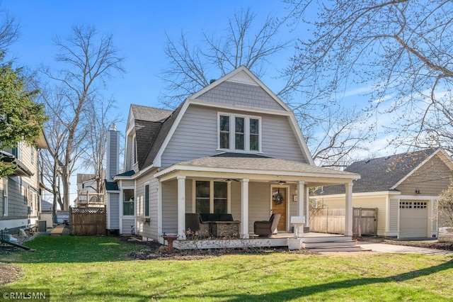 view of front facade featuring a front lawn, fence, covered porch, a gambrel roof, and roof with shingles