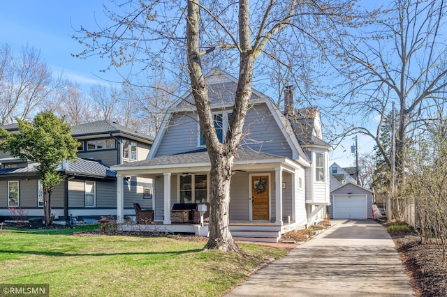 view of front facade with a porch, driveway, a front yard, a garage, and an outdoor structure
