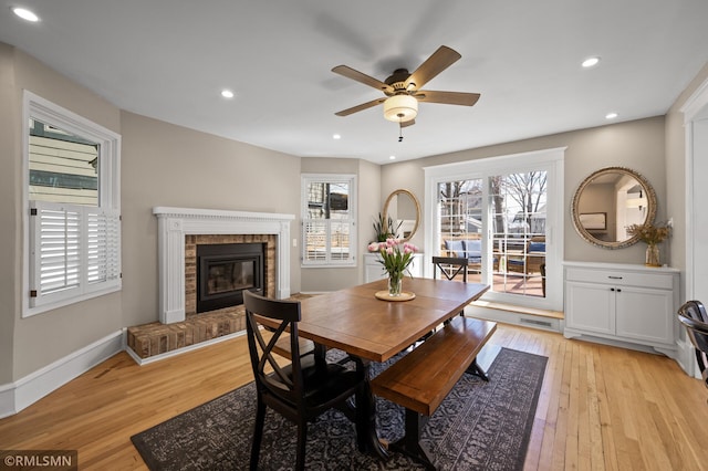 dining space with light wood-style floors, a ceiling fan, a brick fireplace, and recessed lighting