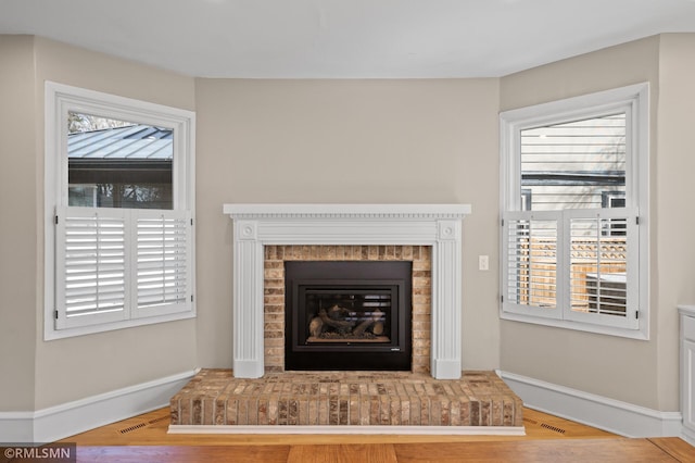 room details featuring a brick fireplace, baseboards, and wood finished floors