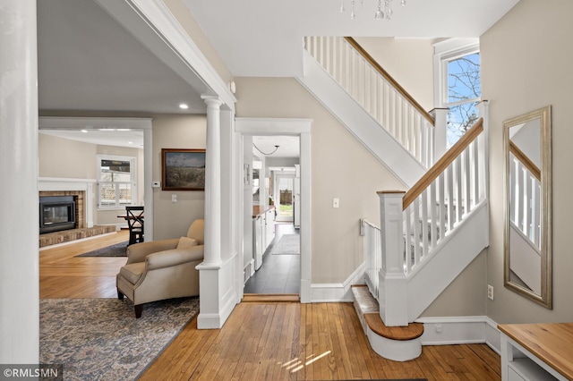 foyer entrance featuring baseboards, a fireplace, a healthy amount of sunlight, and hardwood / wood-style flooring
