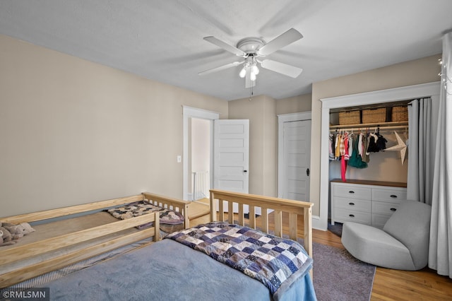 bedroom with ceiling fan, wood finished floors, and a closet
