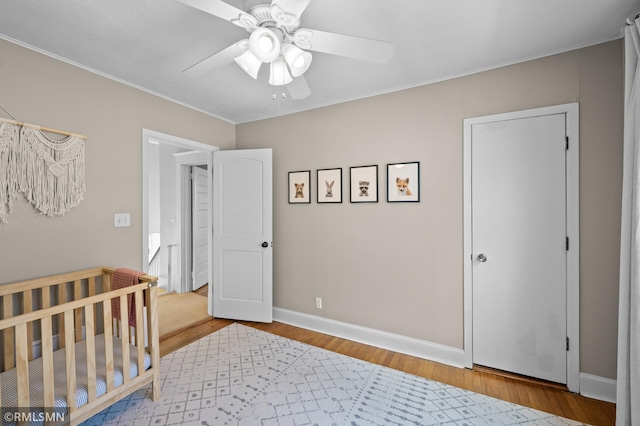 bedroom featuring baseboards, a ceiling fan, crown molding, and wood finished floors