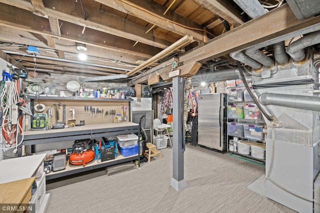 unfinished below grade area with freestanding refrigerator, carpet, and a workshop area