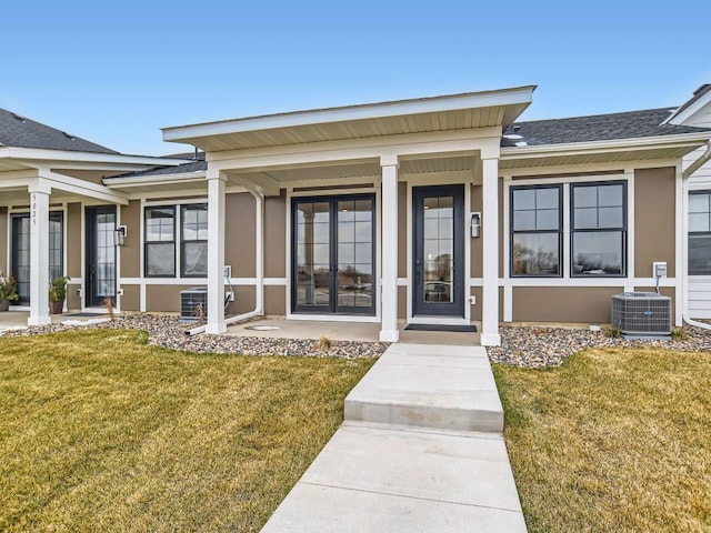 entrance to property with a lawn, central AC unit, and stucco siding