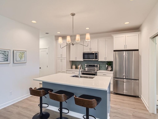 kitchen featuring decorative backsplash, a breakfast bar area, a sink, stainless steel appliances, and light wood-style flooring