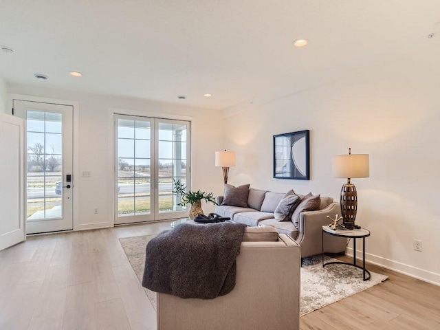 living area featuring baseboards, recessed lighting, and light wood finished floors