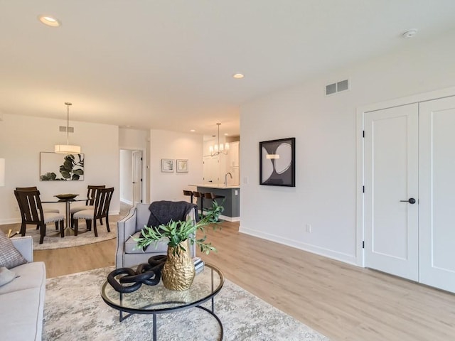 living area with visible vents, baseboards, recessed lighting, light wood-type flooring, and a chandelier