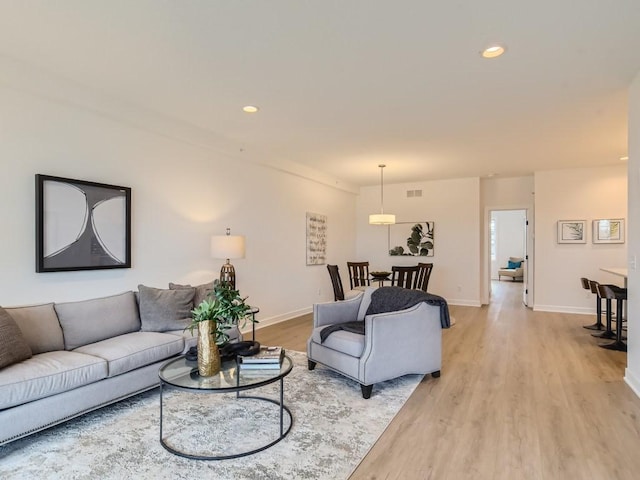 living room featuring recessed lighting, baseboards, visible vents, and light wood-style flooring