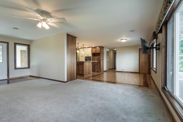 22694 Coney Island Dr, Clitherall, MN 56524 - unfurnished living room featuring carpet floors, plenty of natural light, baseboards, and a ceiling fan