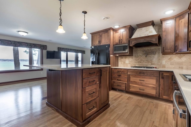22694 Coney Island Dr, Clitherall, MN 56524 - kitchen featuring appliances with stainless steel finishes, custom exhaust hood, light countertops, light wood-style flooring, and tasteful backsplash