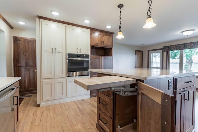 22694 Coney Island Dr, Clitherall, MN 56524 - kitchen with stainless steel oven, light wood-style flooring, decorative light fixtures, white cabinets, and a kitchen island