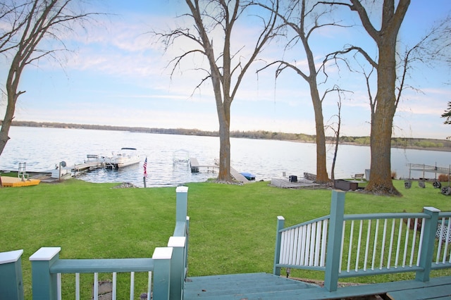 view of dock with a water view and a lawn