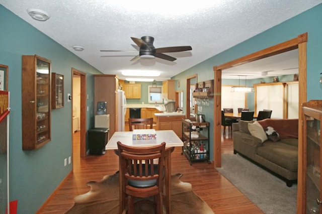 dining area with ceiling fan, a textured ceiling, and dark wood-style flooring