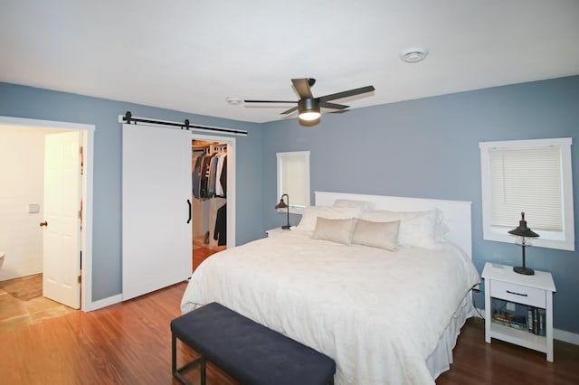 bedroom featuring a closet, wood finished floors, a barn door, and baseboards