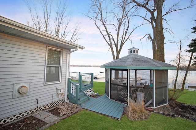 deck with a gazebo, a water view, and a lawn