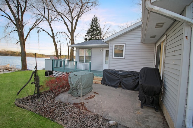 view of patio with area for grilling and a deck with water view