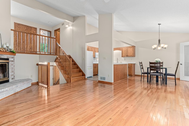 5676 Donegal Dr, Shoreview, MN 55126 - living area featuring lofted ceiling, a brick fireplace, light wood-type flooring, stairs, and a chandelier