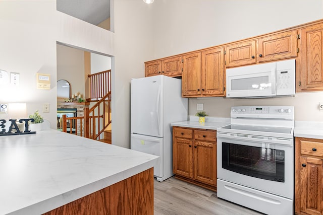 5676 Donegal Dr, Shoreview, MN 55126 - kitchen featuring white appliances, light countertops, light wood-type flooring, brown cabinets, and a towering ceiling