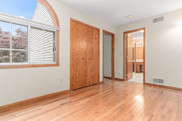 5676 Donegal Dr, Shoreview, MN 55126 - unfurnished bedroom featuring light wood-style flooring, baseboards, a closet, and ensuite bathroom