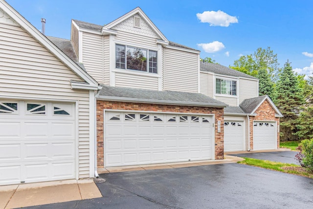 5676 Donegal Dr, Shoreview, MN 55126 - townhome / multi-family property with roof with shingles, brick siding, asphalt driveway, and a garage