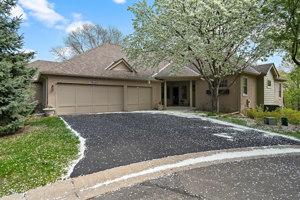 19010 Ashcroft Cir, Minnetonka, MN 55345 - ranch-style home with driveway, a garage, a shingled roof, and stucco siding
