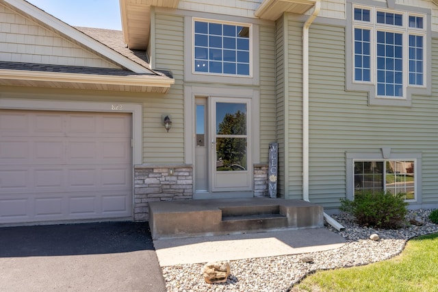 822 Emerson Ave N, Montrose, MN 55363 - view of exterior entry featuring stone siding, roof with shingles, and a garage