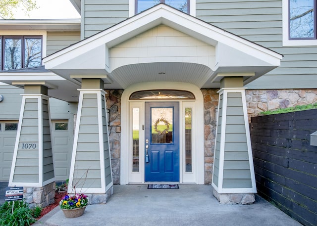 view of exterior entry featuring fence and stone siding