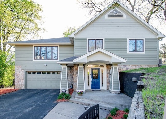 view of front of property with stone siding, an attached garage, and driveway