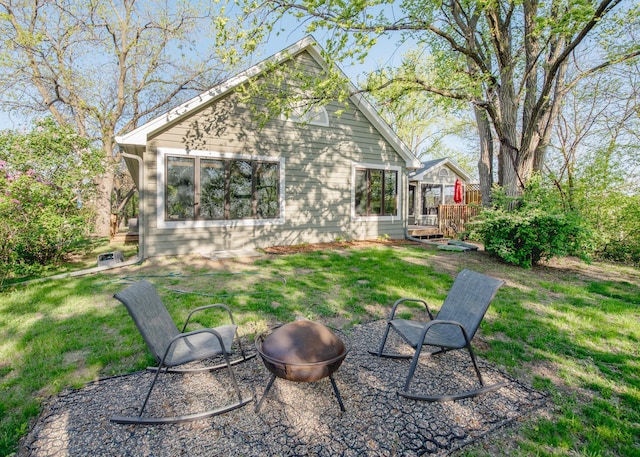 view of green lawn featuring an outdoor fire pit and a wooden deck