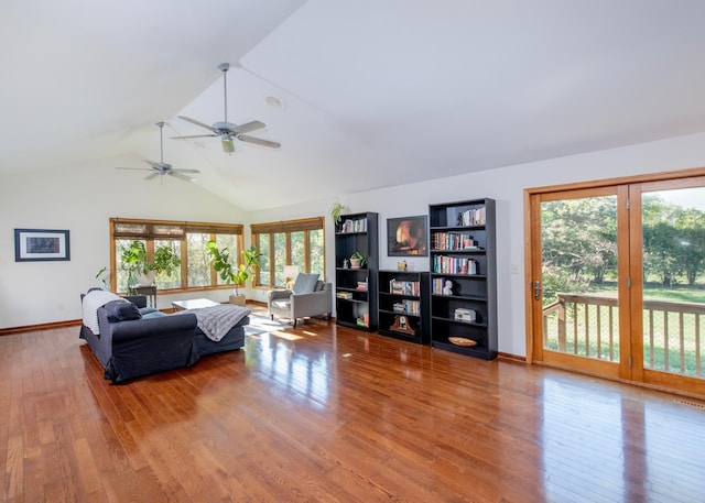 living area with healthy amount of natural light, wood finished floors, a ceiling fan, high vaulted ceiling, and baseboards