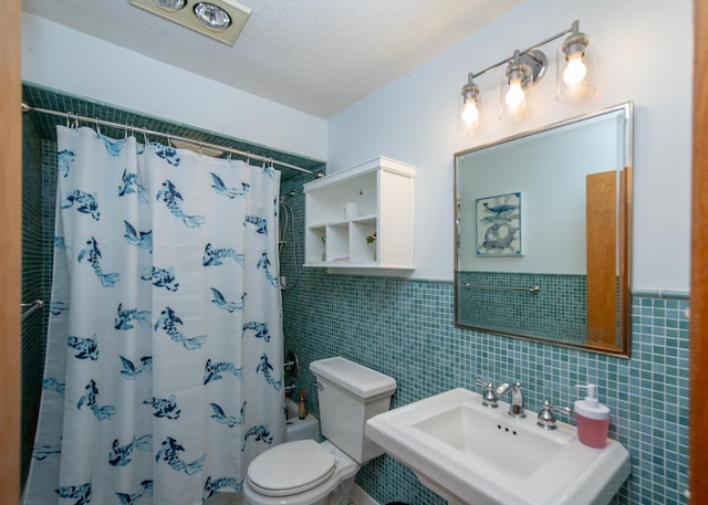 bathroom with a sink, tile walls, toilet, a textured ceiling, and shower / bathtub combination with curtain