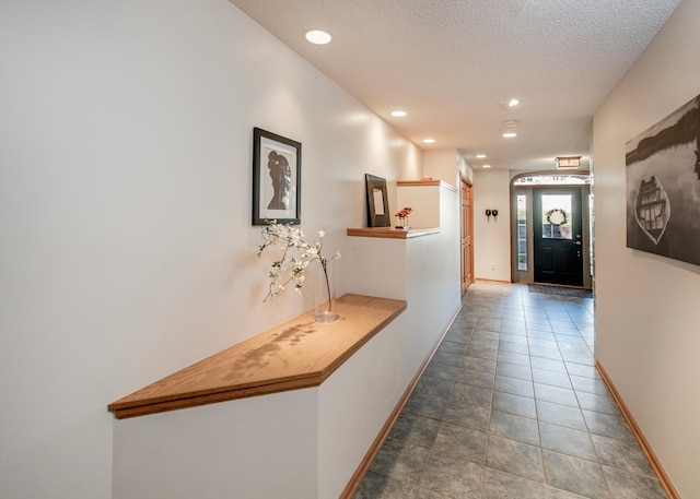 corridor with baseboards, recessed lighting, and a textured ceiling