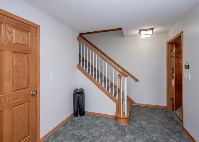 foyer with a textured ceiling, stairway, and baseboards