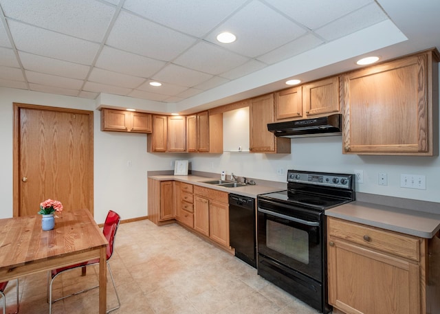 kitchen with black appliances, under cabinet range hood, a sink, a paneled ceiling, and baseboards