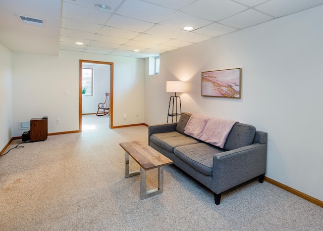 carpeted living area featuring baseboards and a paneled ceiling