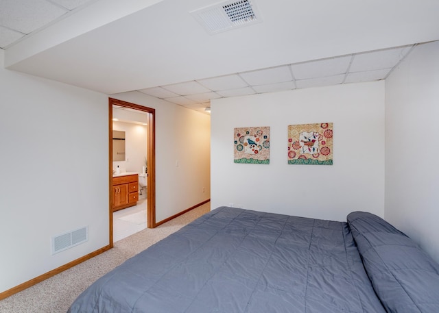 bedroom with a paneled ceiling, light carpet, baseboards, and connected bathroom
