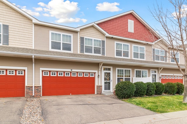 multi unit property with an attached garage, driveway, and brick siding