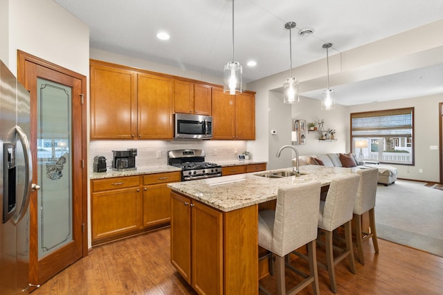 kitchen with a sink, brown cabinetry, stainless steel appliances, and open floor plan
