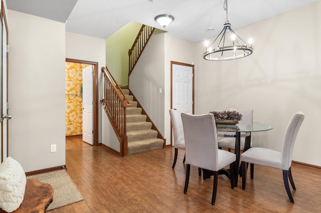 dining space featuring stairs, baseboards, a chandelier, and wood-type flooring